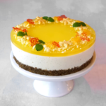 Julecheesecake med appelsingelé pyntet med appelsin, citronmelisse, hvid chokolade og orange koraller