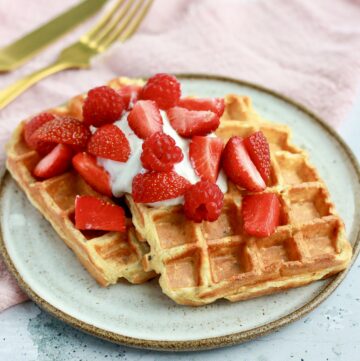 Belgiske morgenmadsvafler med havregryn og skyr toppet med friske jordbær, serveret på en grå tallerken