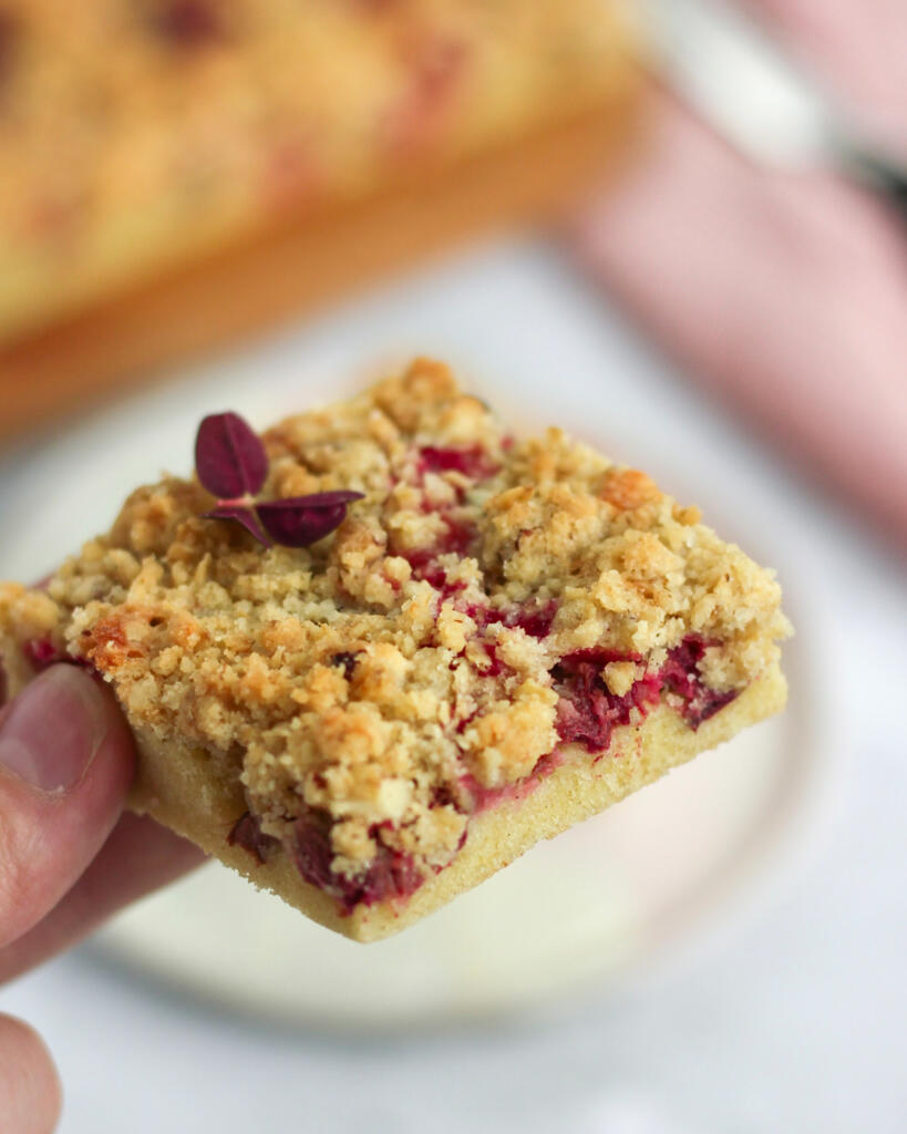 Nærbillede af et stykke rabarber crumble kage med synlige rabarberstykker og sprød crumble topping