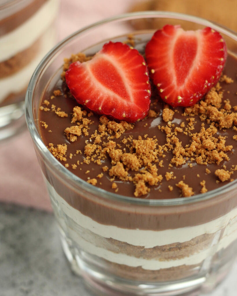 Nærbillede af Biscoff cheesecake i glas med chokoladeganache, knuste Lotus-kiks og friske jordbær som nem dessert i glas