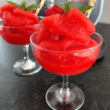 Strawberry daiquiri slush ice i to cocktailglas foran slush ice maskine pyntet med jordbær og mynte