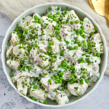 Kartoffelsalat med græsk yoghurt, ærter og purløg serveret i hvid skål med guldske