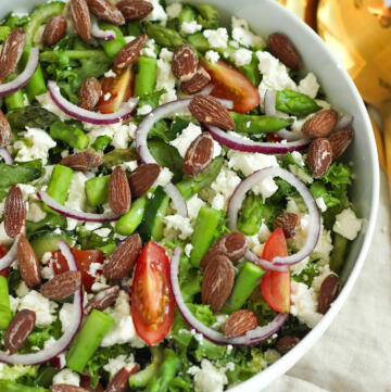 Salat med grønne asparges, feta, cherrytomater, rødløg og saltmandler serveret i hvid skål