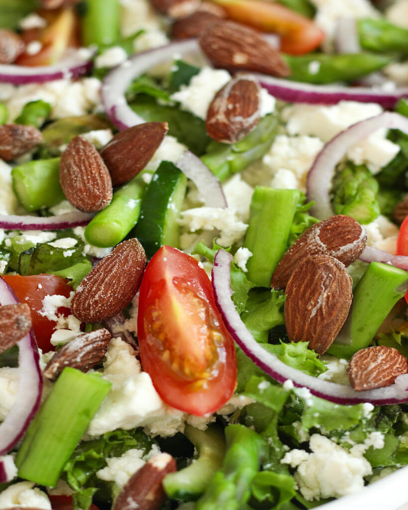 Nærbillede af salat med asparges, smuldret feta, cherrytomater og saltmandler