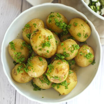 Kartofler med persille og smør set oppefra med friskhakket persille og skinnende smeltet smør