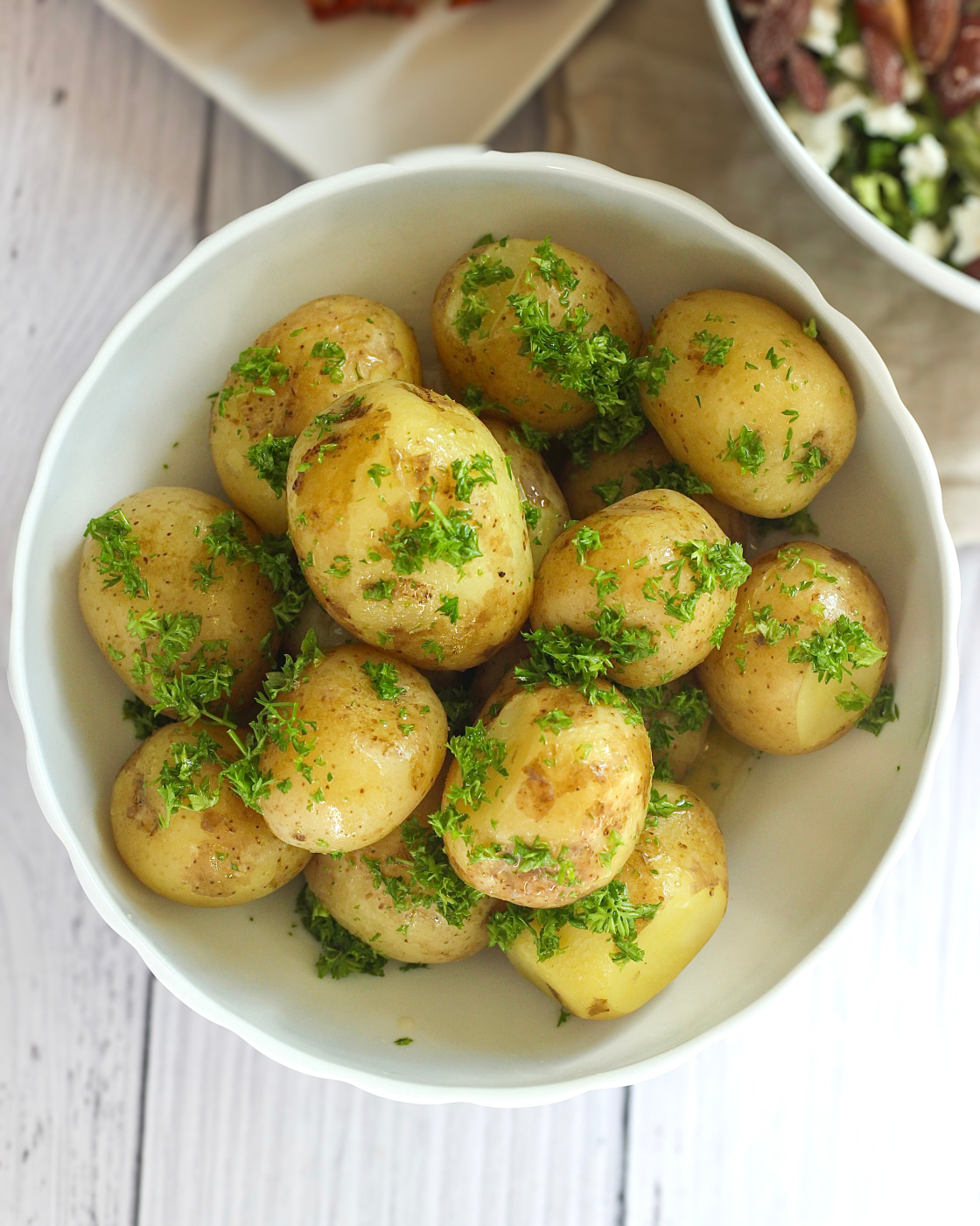 Kartofler med persille og smør set oppefra med friskhakket persille og skinnende smeltet smør