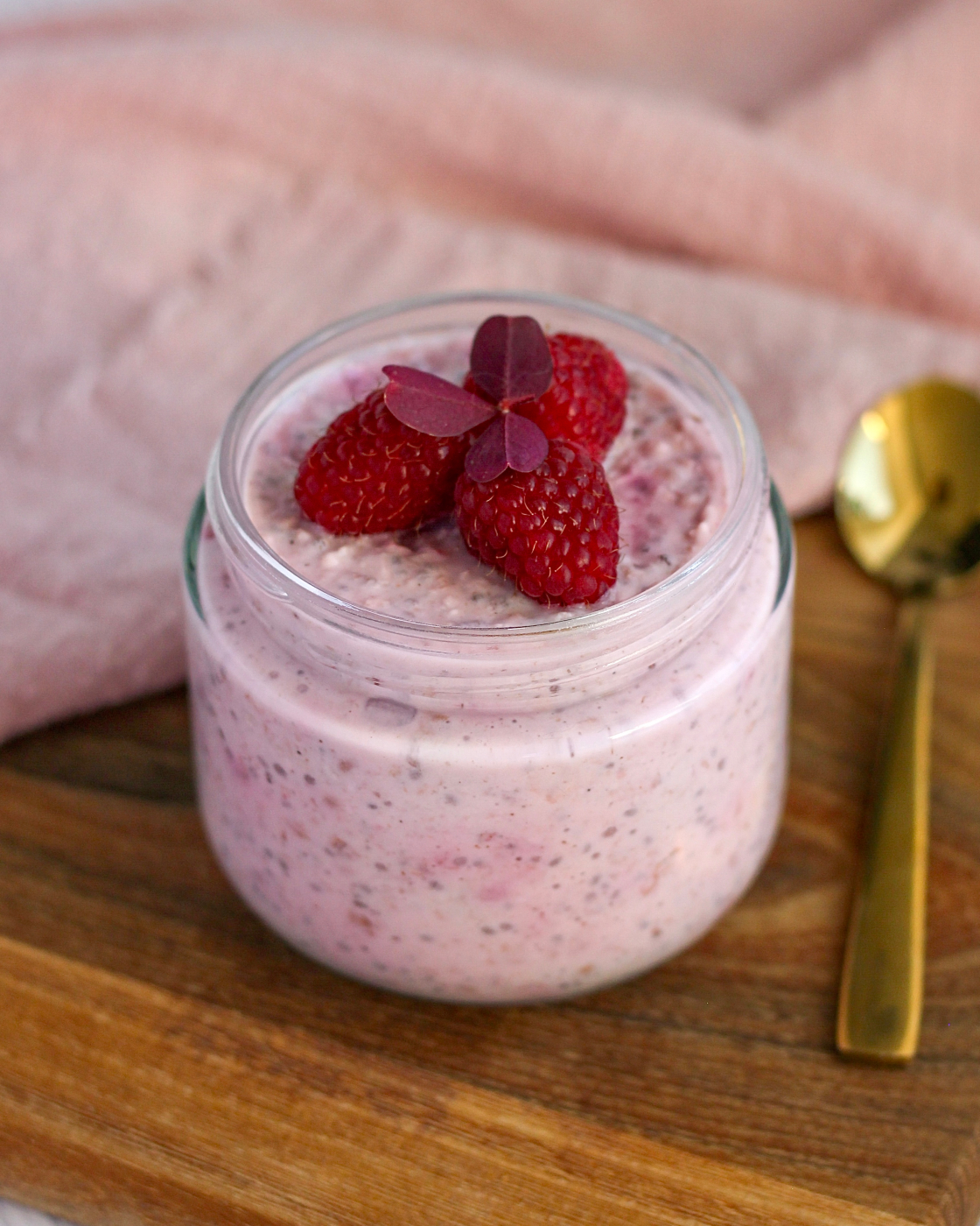 Cremet overnight oats med skyr, chiafrø og moste hindbær serveret i glas med guldske