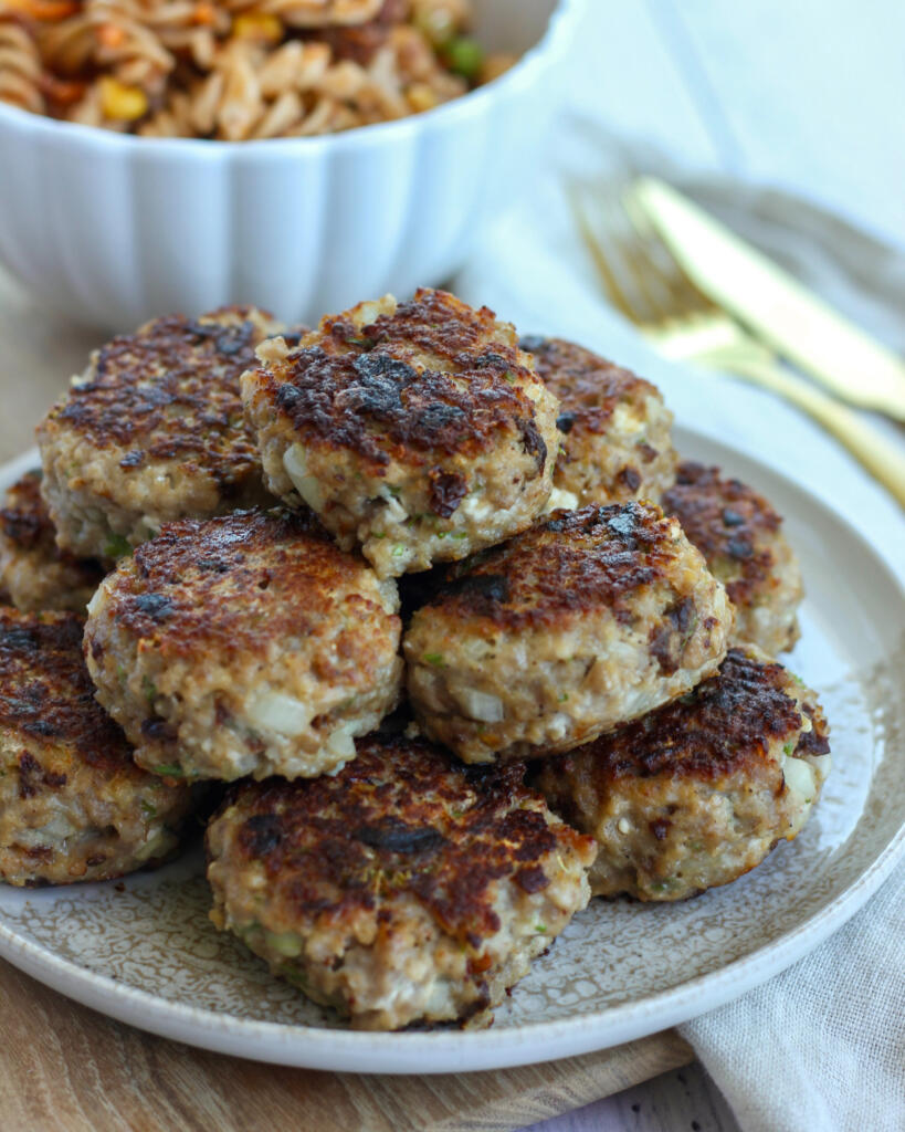 Græske frikadeller med feta og soltørrede tomater stablet på tallerken serveret med pastasalat
