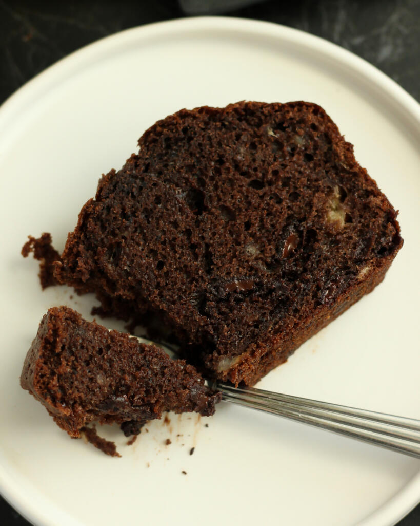 Nærbillede af saftig chokoladekage med banan på tallerken med smeltede stykker mørk chokolade