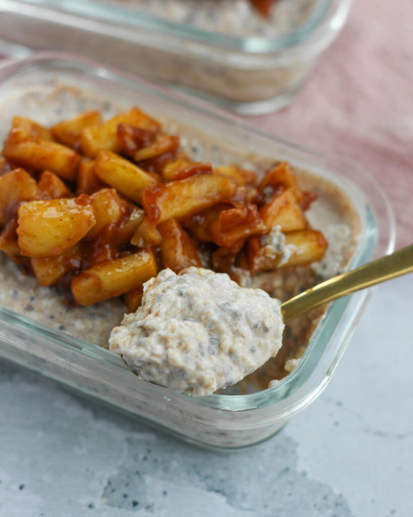 Nærbillede af ske med cremet overnight oats med chia og skyr fra glasbøtte toppet med kanelæbler