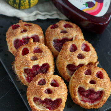 Små Halloween tærter formet som græskar med ansigter af butterdej, fyldt med marcipan og boysenbærmarmelade og drysset med kanelsukker