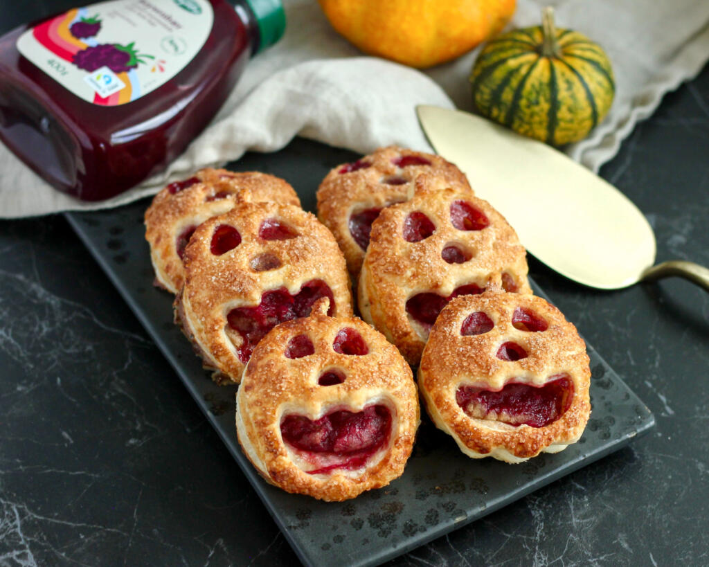 Små Halloween tærter formet som græskar med ansigter af butterdej, fyldt med marcipan og boysenbærmarmelade og drysset med kanelsukker