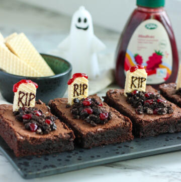 Halloween brownies med gravsten af vaniljevafler med RIP skrevet i chokolade, kiksejord og hindbærmarmelade som blod