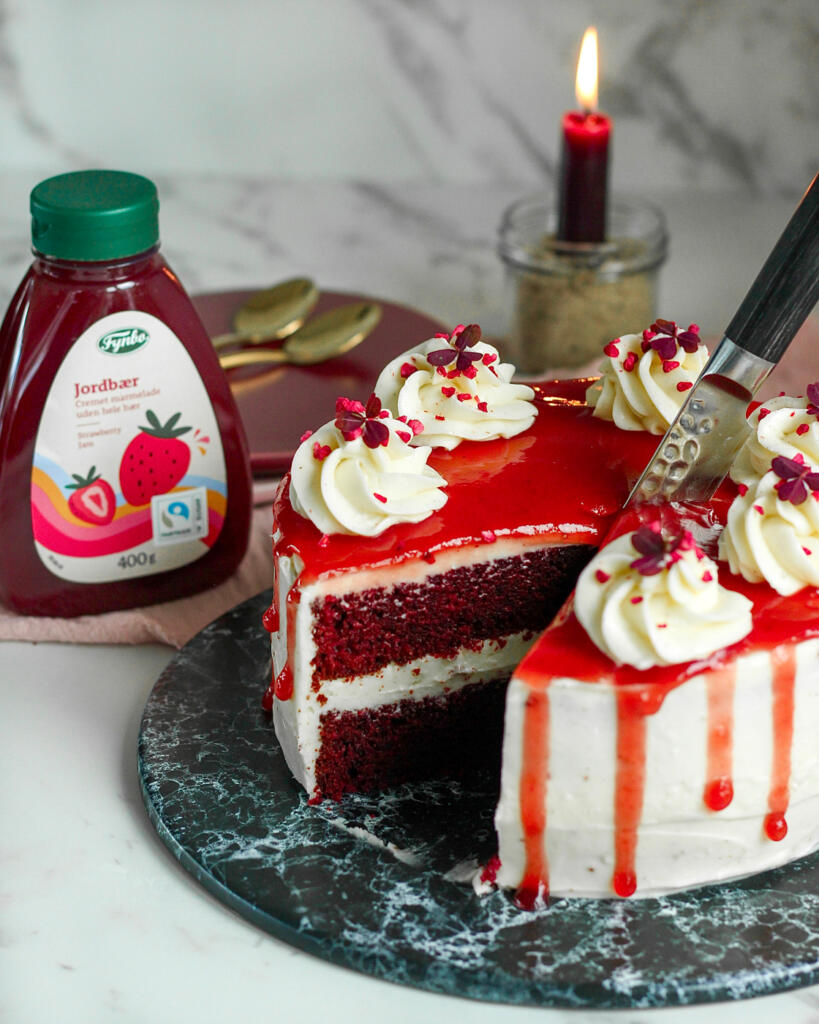 Blodig Halloween kage med et stykke skåret ud, så man kan se de røde red velvet bunde og cream cheese frosting